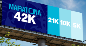 Outdoor publicitário da Maratona de Tubarão 2026 exibindo as distâncias de 42K, 21K, 10K e 5K em diferentes tons de azul. No canto direito, o logotipo do evento com a data 24 de maio de 2026 sobre um fundo de céu azul e árvores.