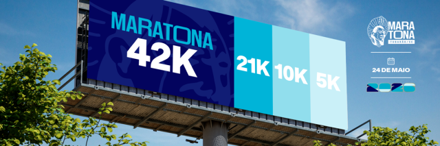 Outdoor publicitário da Maratona de Tubarão 2026 exibindo as distâncias de 42K, 21K, 10K e 5K em diferentes tons de azul. No canto direito, o logotipo do evento com a data 24 de maio de 2026 sobre um fundo de céu azul e árvores.