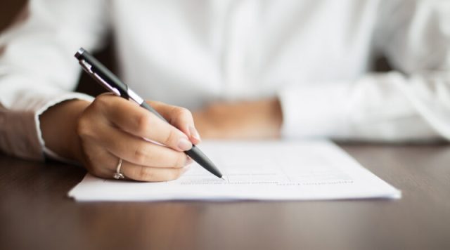Hand of businesswoman writing on document at table