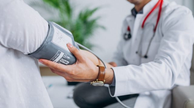 Young male psysician with patient measuring blood pressure