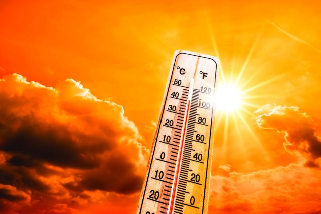 Hot summer or heat wave background, glowing sun on orange sky wi